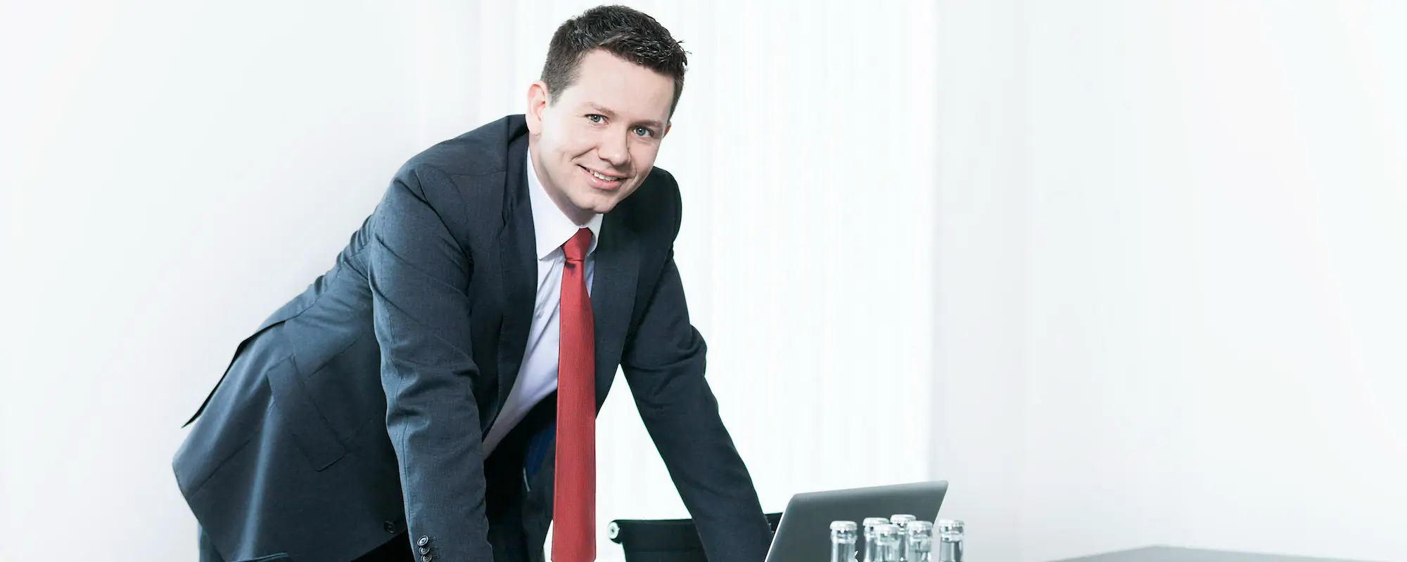 Rechtsanwalt Michael Neugebauer, Fachanwalt für Handels- und Gesellschaftsrecht, Insolvenz- und Sanierungsrecht sowie Steuerrecht bei FRH Erfurt, steht lächelnd am Besprechungstisch.