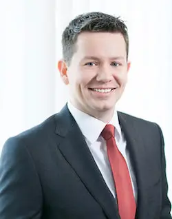 Rechtsanwalt Michael Neugebauer, Fachanwalt für Handels- und Gesellschaftsrecht, Insolvenz- und Sanierungsrecht sowie Steuerrecht bei FRH Erfurt, steht lächelnd am Besprechungstisch.